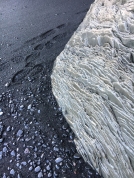 Black sand, footprints and interesting rock textures mix.